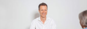 Chirstoph lächelt sympathisch im Gespräch mit einer Klientin.